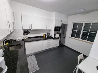 a white kitchen with white cabinets and black appliances at Olimpia Gardens View by Rentallido in Funchal