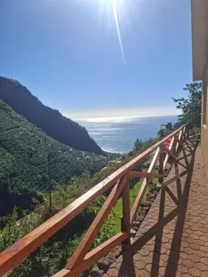 a wooden bridge with the ocean in the background at Levadinha - Nature guest house in Madalena do Mar