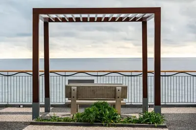 a wooden bench sitting under a pavilion near the ocean at Apt 'A Gaioa' in 'The Cliff Coast Accomodation' in Paul do Mar