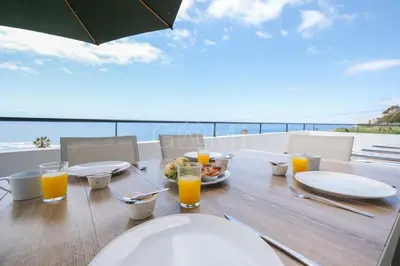 a table with a plate of food and glasses of orange juice at Esterinha's Ocean Apartment by GALMI in Jardim do Mar