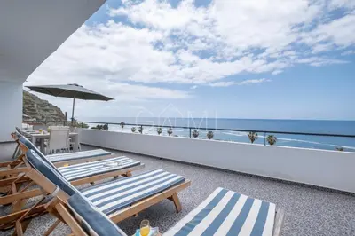 a balcony with chairs and an umbrella and the ocean at Esterinha's Ocean Apartment by GALMI in Jardim do Mar