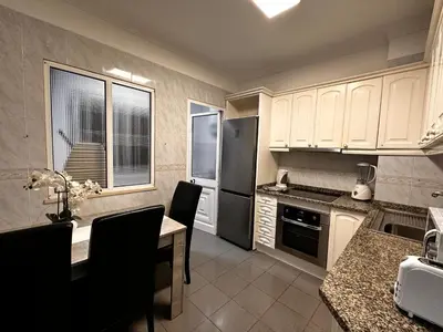 a kitchen with white cabinets and a table with chairs at SÃO GONÇALO APARTAMENTO in Funchal