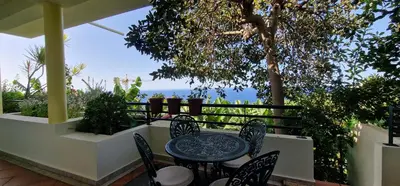 a table and chairs on a patio with a view of the ocean at Sunny Arco Retreat in Arco da Calheta