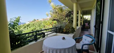 a table and a chair on a balcony with a view at Sunny Arco Retreat in Arco da Calheta