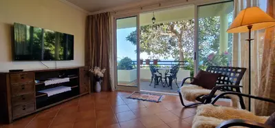 a living room with a television and a table with chairs at Sunny Arco Retreat in Arco da Calheta