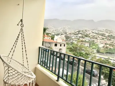 a hammock on a balcony with a view of a city at Gemini Apartment by AM in Funchal
