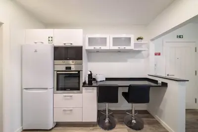 a kitchen with white appliances and black counter tops at Casa da Clara by MTH in Caniço