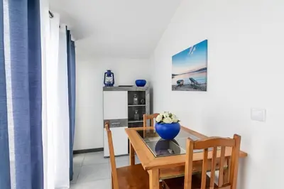a dining room table with a blue vase on it at Esterinha's Sunset Apartment by GALMI in Estreito da Calheta