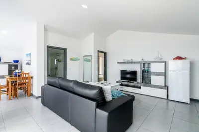 a living room with a black leather couch and a kitchen at Esterinha's Sunset Apartment by GALMI in Estreito da Calheta