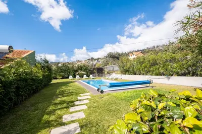 a swimming pool in a yard with a grass field at De Casa Villa by GALMI in Estreito da Calheta