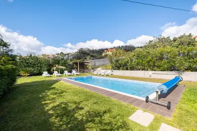 a pool with a blue slide in a yard at De Casa Villa by GALMI in Estreito da Calheta