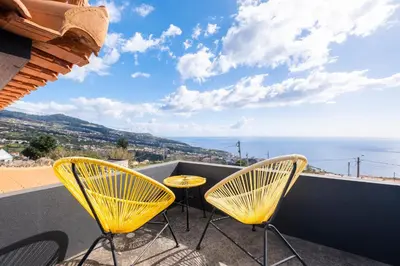 a balcony with yellow chairs and a view of the ocean at De Casa Villa by GALMI in Estreito da Calheta