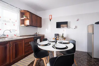 a kitchen with a table with chairs and a refrigerator at De Casa Villa by GALMI in Estreito da Calheta