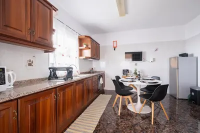 a kitchen with wooden cabinets and a table with chairs at De Casa Villa by GALMI in Estreito da Calheta