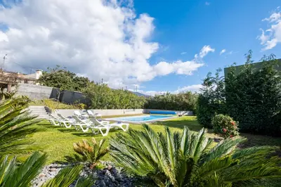 a garden with a swimming pool and lawnitures at De Casa Villa by GALMI in Estreito da Calheta