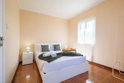 a bedroom with a large white bed and a window at Villa Pequenino by GALMI in Estreito da Calheta
