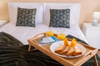 a breakfast tray with toast and orange juice on a bed at Villa Pequenino by GALMI in Estreito da Calheta