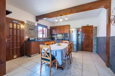 a kitchen with a table with chairs and a refrigerator at Casa del Mar II by GALMI in Arco de São Jorge