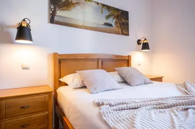 a bedroom with a bed with white sheets and two lights at Casa del Mar II by GALMI in Arco de São Jorge