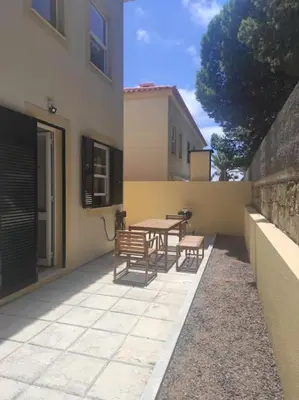 a patio with a table and benches next to a building at Casa das Lombas in Vila Baleira