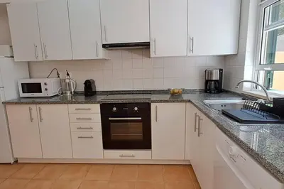 a kitchen with white cabinets and a black oven at Casa das Lombas in Vila Baleira