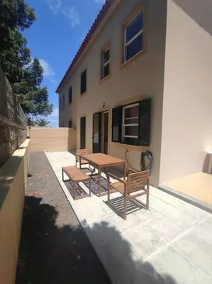 a picnic table and two benches in front of a building at Casa das Lombas in Vila Baleira