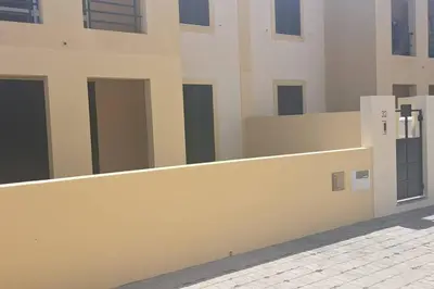 a white building with a fence next to a sidewalk at Casa das Lombas in Vila Baleira