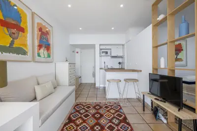 a living room with a white couch and a kitchen at Studio Mar - By WeHost in Funchal