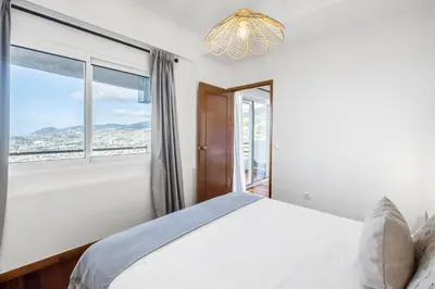 a bedroom with a bed and a large window at Casa da Angela - By WeHost in Funchal