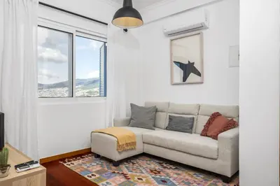 a living room with a couch and a window at Casa da Angela - By WeHost in Funchal