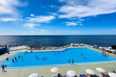 a large swimming pool next to the ocean at Casa Branca Apartment in Funchal in Funchal