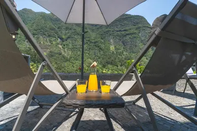 a table with two glasses of orange juice and an umbrella at Mystic Mountain by Atlantic Holiday in São Vicente