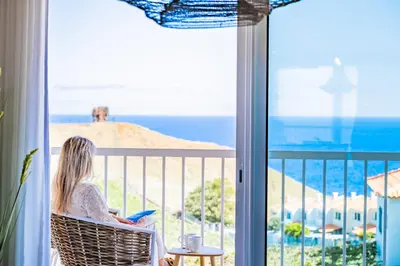 a woman sitting in a chair looking out a window at the ocean at Hideaway Apartment by Homie in Caniço