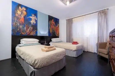 a bedroom with two beds and a painting on the wall at By the Atlantic Apartments 3-bedroom in Funchal