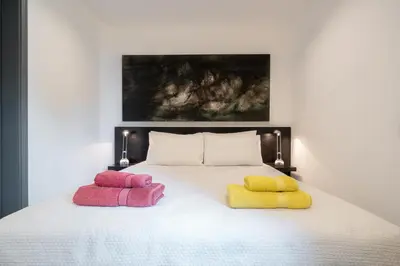 a bed with three colorful pillows on it at By the Atlantic Apartments 3-bedroom in Funchal