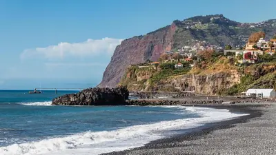 a rocky beach with houses on the side of a mountain at By the Atlantic Apartments 3-bedroom in Funchal