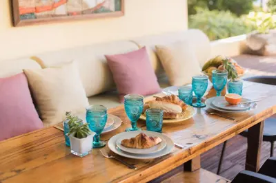 a wooden table with plates of food and blue glasses at By the Atlantic Apartments 3-bedroom in Funchal