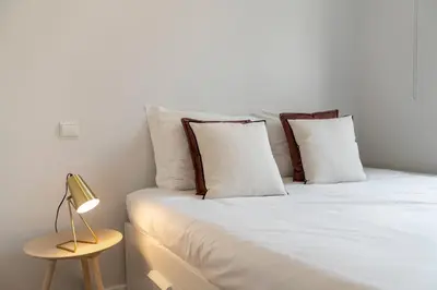 a bed with white sheets and pillows next to a lamp at Vista Formosa I by An Island Apart in Funchal