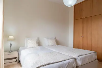 a bedroom with a white bed and a wooden cabinet at Villa Areal Porto Santo - By An Island Apart in Porto Santo
