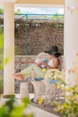 a woman in a hat sitting on a chair at Villa Areal Porto Santo - By An Island Apart in Porto Santo