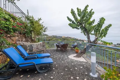 a pair of blue chairs on a balcony overlooking the ocean at Casa da Vizinha in Ponta do Sol