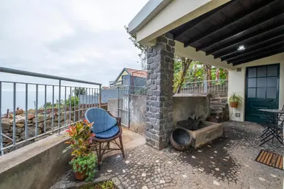 a patio with a brick fireplace and a chair at Casa da Vizinha in Ponta do Sol