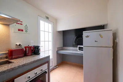 a kitchen with a white refrigerator and a window at Casa da Vizinha in Ponta do Sol
