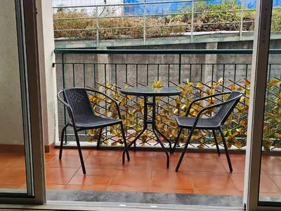 a patio table and two chairs on a balcony at Milagrosa Apartment in Caniço