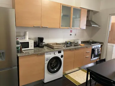 a kitchen with a washing machine and a microwave at Milagrosa Apartment in Caniço