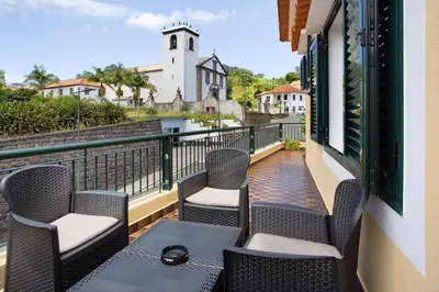 a balcony with chairs and a table with a view of a church at Casa do tio Inácio in Santana