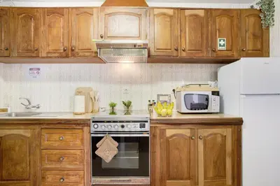 a kitchen with wooden cabinets and a stove and a microwave at Casa do tio Inácio in Santana