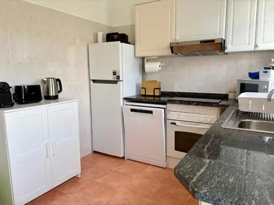 a kitchen with white cabinets and a white refrigerator at Beach Relax Apartment in Porto Santo