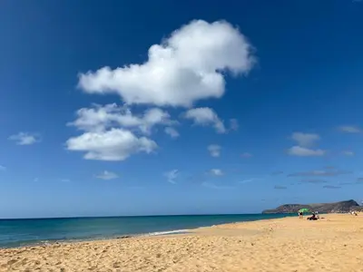 a beach with people sitting on the sand and the ocean at Beach Relax Apartment in Porto Santo