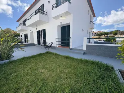 a white house with a lawn in front of it at Beach Relax Apartment in Porto Santo